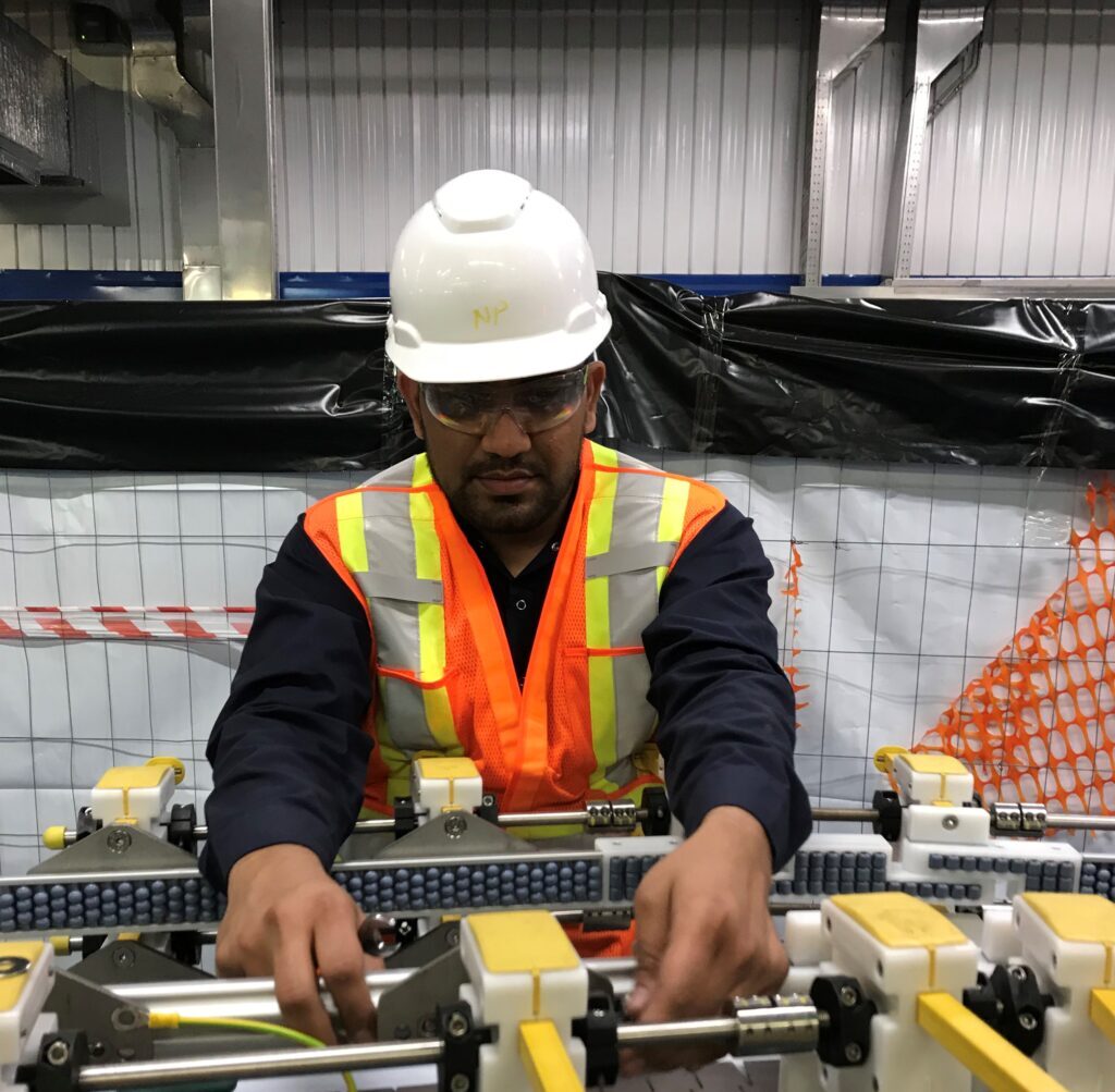 A service technician working on an adjustable guide rail system on a conveyor